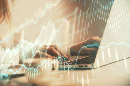 Double exposure of woman hands working on computer and forex graph hologram drawing. Financial...