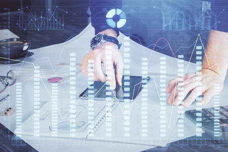 Double exposure of mans hands holding and using a digital device and forex graph drawing. Financial market concept.の写真素材