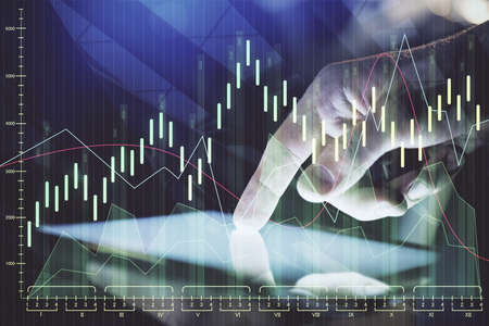 Double exposure of mans hands holding and using a digital device and forex graph drawing. Financial...