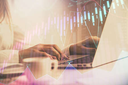 Double exposure of woman hands working on computer and forex graph hologram drawing. Financial...