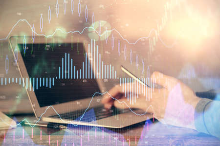 Double exposure of mans hands holding and using a digital device and forex graph drawing. Financial...