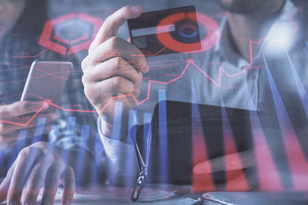 Double exposure of man and woman on-line shopping holding a credit card and forex graph hologram...