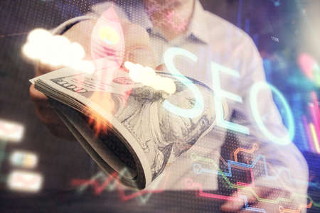 Multi exposure of seo drawing hologram and us dollars bills and man hands.の写真素材