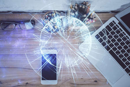 Double exposure of business theme hologram over desktop with phone. Top view. Mobile international...