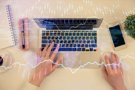 Double exposure of woman hands working on computer and forex chart hologram drawing. Top View....