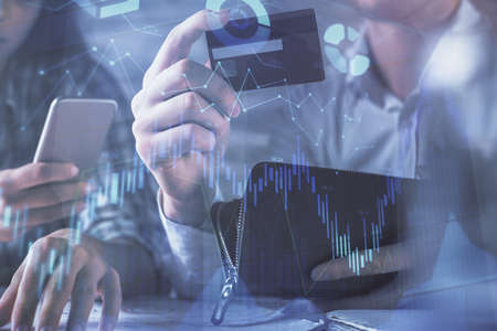 Double exposure of man and woman on-line shopping holding a credit card and forex graph hologram...