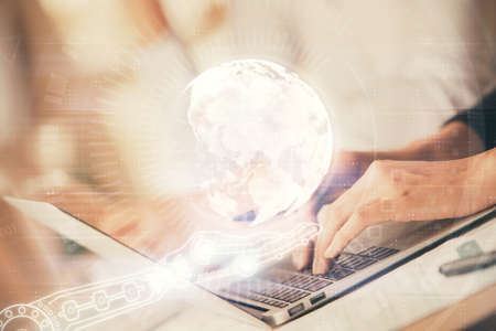 Double exposure of woman hands working on computer and world map hologram drawing. International...