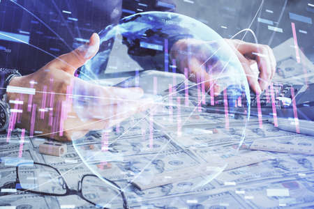 Double exposure of mans hands holding and using a digital device and forex graph drawing. Financial market concept.の写真素材