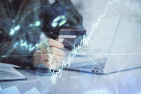 Multi exposure of woman on-line shopping holding a credit card and financial graph drawing. Stock...