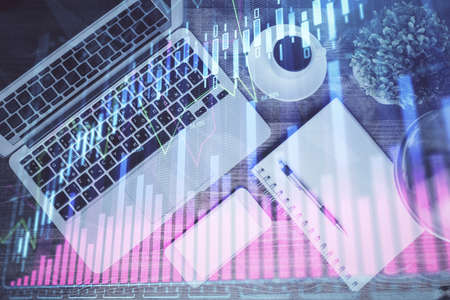 Financial market graph and top view computer on the desktop background. Double exposure. Investment...