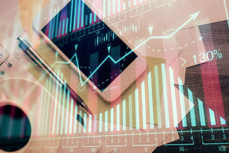 Multi exposure of forex graph hologram over desktop with phone. Top view. Mobile trade platform...