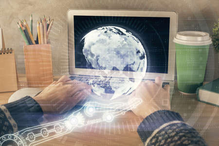 Double exposure of woman hands working on computer and world map hologram drawing. International technology business concept.の写真素材