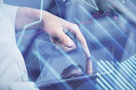 Double exposure of mans hands holding and using a digital device and forex graph drawing. Financial...