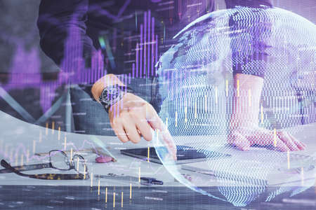 Double exposure of mans hands holding and using a digital device and forex graph drawing. Financial...