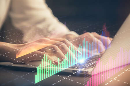 Double exposure of businesswoman hands typing on computer and forex chart hologram drawing....