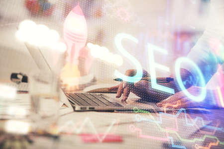 Double exposure of woman hands working on computer and seo hologram drawing. internet search concept.の写真素材