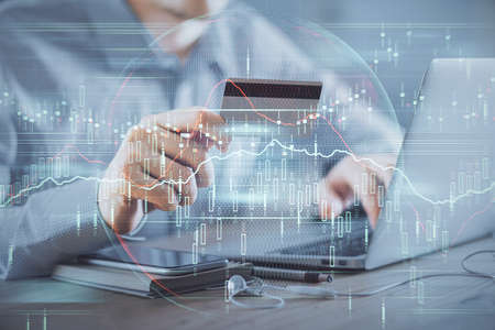 Double exposure of man hands holding a credit card and Forex graph drawing. Stock trading and...