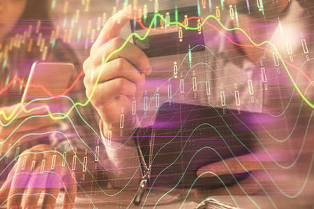 Double exposure of man and woman on-line shopping holding a credit card and forex graph hologram...