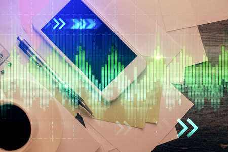 Multi exposure of forex graph hologram over desktop with phone. Top view. Mobile trade platform...