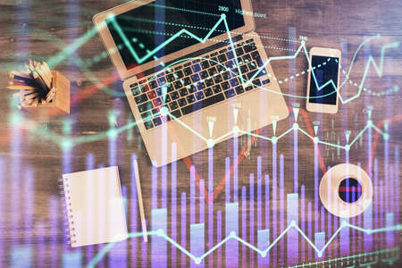 Double exposure of forex chart drawing over table background with computer. Concept of financial...