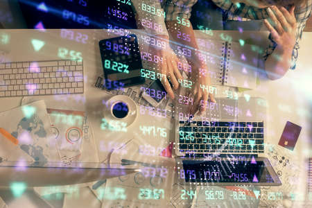 Double exposure of man and woman working together and financial graph hologram drawing. market analysis concept. Computer background. Top View.の写真素材