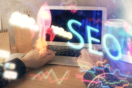Double exposure of woman hands working on computer and seo hologram drawing. internet search...