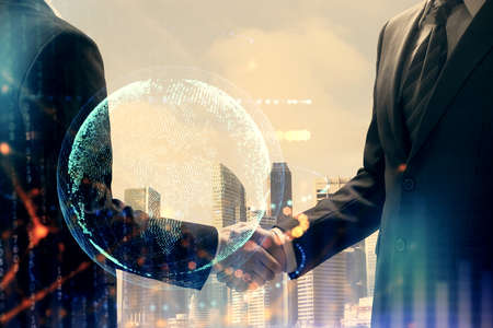 Double exposure of world map hologram and handshake of two men. International partnership concept.の写真素材