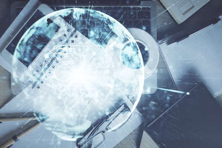 Double exposure of business theme hologram over desktop with phone. Top view. Mobile international...