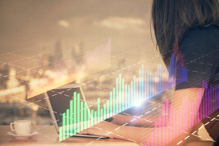 Double exposure of businesswoman hands typing on computer and forex chart hologram drawing....