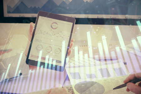 Double exposure of mans hands holding and using a digital device and forex graph drawing. Financial market concept.の写真素材