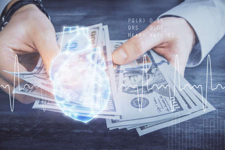 Multi exposure of heart drawing hologram and USA dollars bills and man hands. Medical education