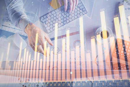 Multi exposure of mans hands typing over computer keyboard and forex graph hologram drawing. Top...
