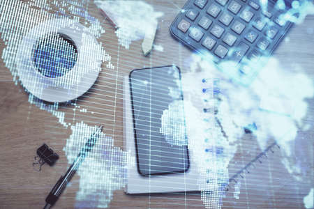 Double exposure of business theme hologram over desktop with phone. Top view. Mobile international trade connection concept.の写真素材