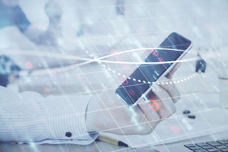 Double exposure of mans hands holding and using a digital device and forex graph drawing. Financial...