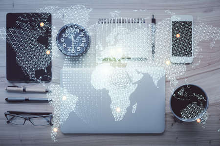 Double exposure of business theme hologram over desktop with phone. Top view. Mobile international...