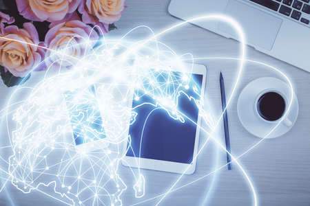 Double exposure of business theme hologram over desktop with phone. Top view. Mobile international...
