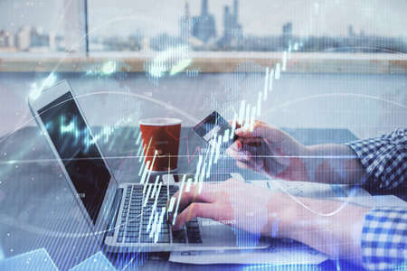 Double exposure of man hands holding a credit card and Forex graph drawing. Stock trading and...