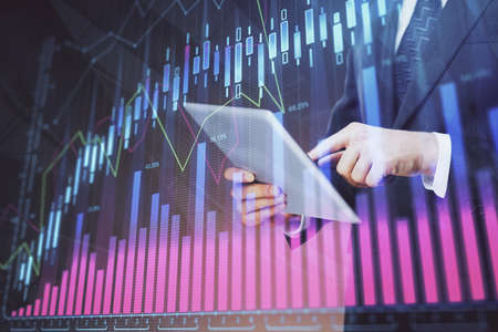 Double exposure of mans hands holding and using a digital device and forex graph drawing. Financial...