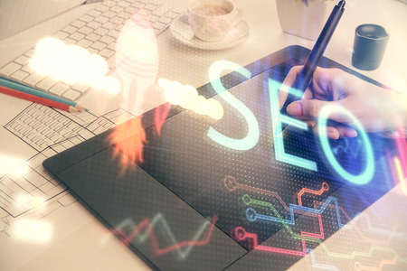 Double exposure of SEO sketch hologram and woman holding and using a mobile device.