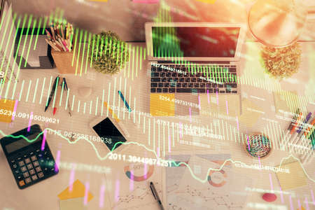 Double exposure of forex chart drawing over table background with computer. Concept of financial...