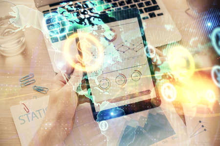 Double exposure of mans hands holding and using a digital device and forex graph drawing. Financial...