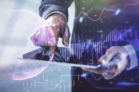 Double exposure of mans hands holding and using a digital device and forex graph drawing. Financial market concept.の写真素材