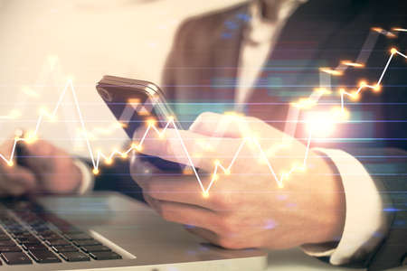 Multi exposure of mans hands holding and using a digital phone and forex graph drawing. Financial...
