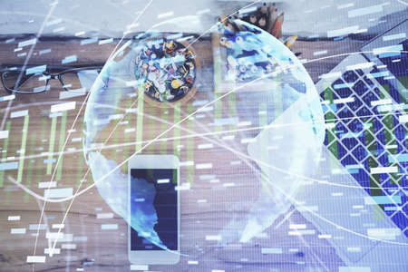 Double exposure of business theme hologram over desktop with phone. Top view. Mobile international trade connection concept.の写真素材