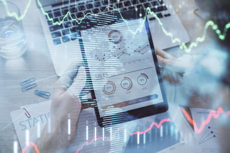 Double exposure of mans hands holding and using a digital device and forex graph drawing. Financial...