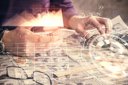 Double exposure of mans hands holding and using a digital device and forex graph drawing. Financial market concept.の写真素材