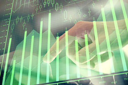 Multi exposure of mans hands holding and using a digital phone and forex graph drawing. Financial...