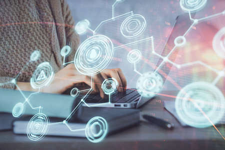 Double exposure of woman hands typing on computer and social network theme hologram drawing. People...