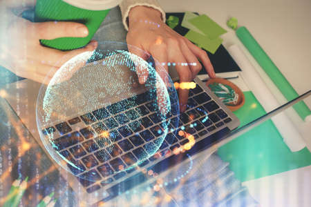 Double exposure of woman hands working on computer and world map hologram drawing. International...