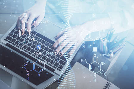 Double exposure of woman hands typing on computer and DNA hologram drawing. Medical education concept.の写真素材